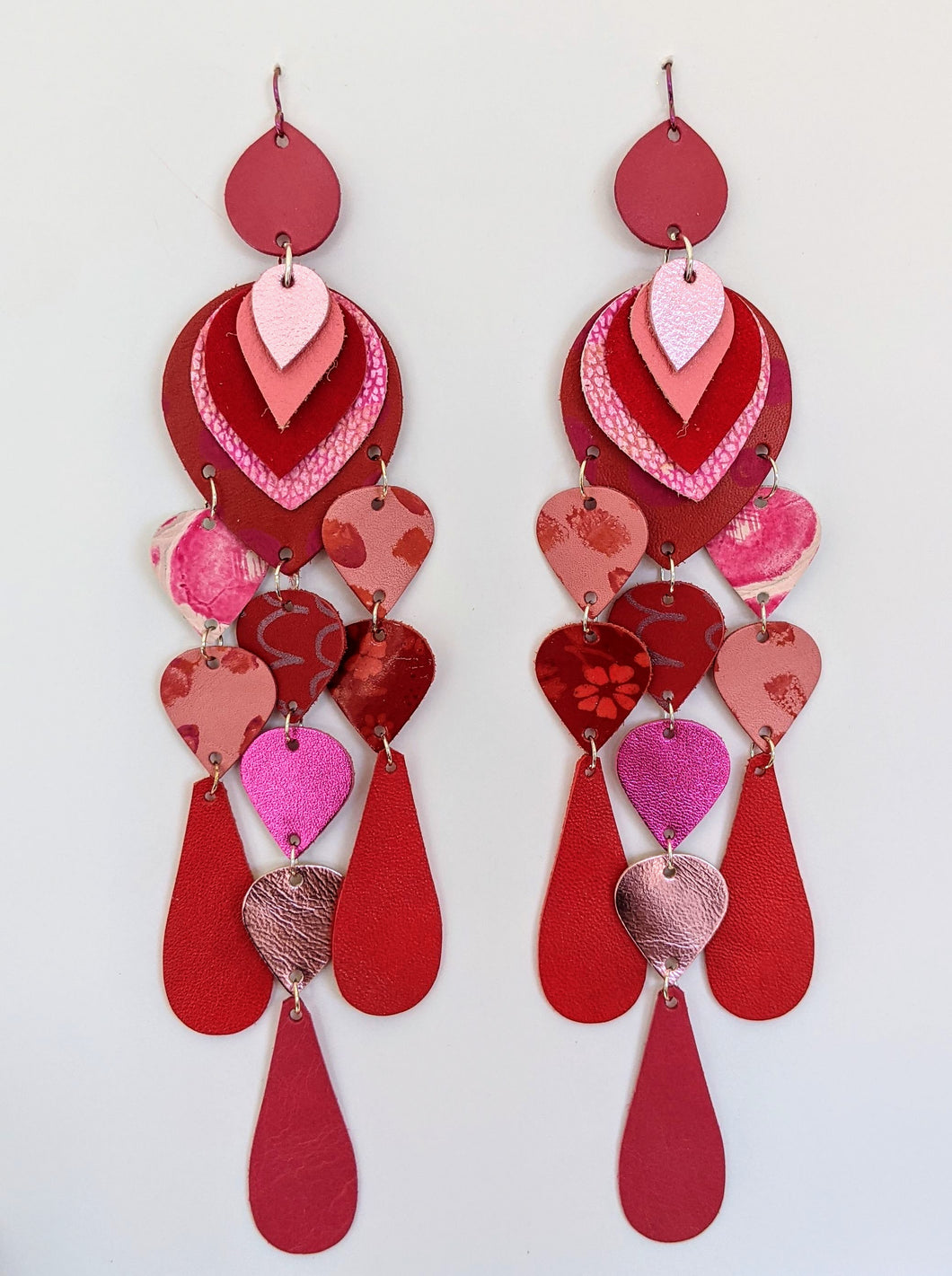 Red and pink statement earrings handmade from leather. Long dangles of small colourful pieces in strawberry pinks and reds.